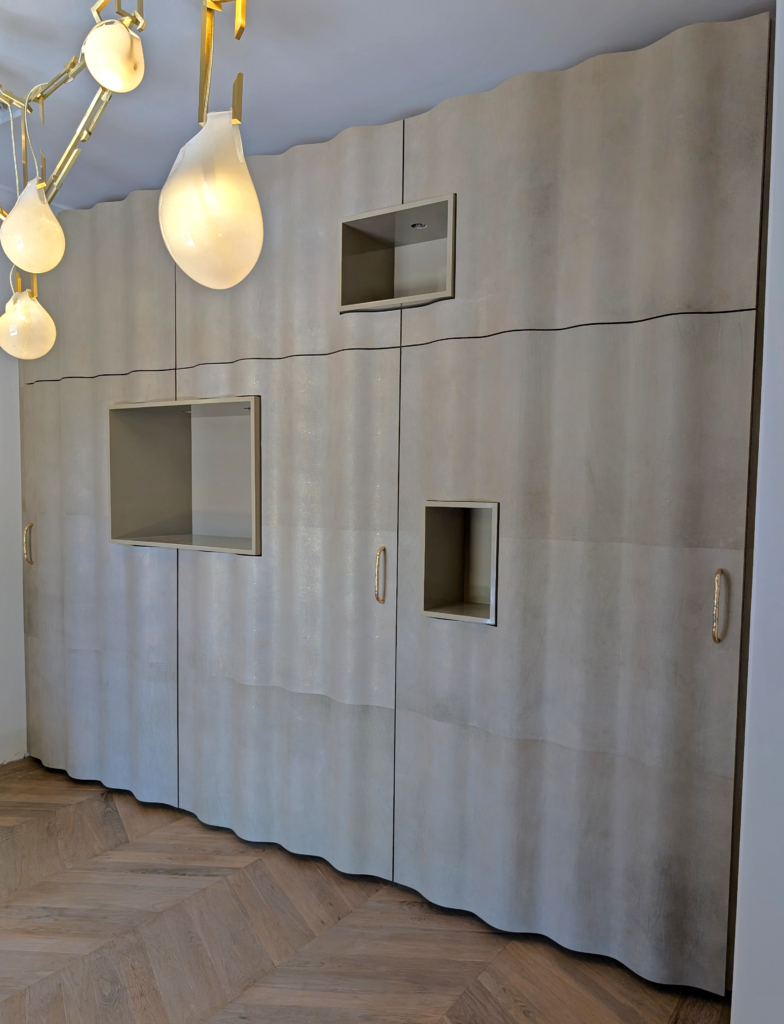 Custom Cabinetry, entry wall, with it’s custom bent laminated doors, opens up to reveal a fully fitted closet interior in bleached walnut.