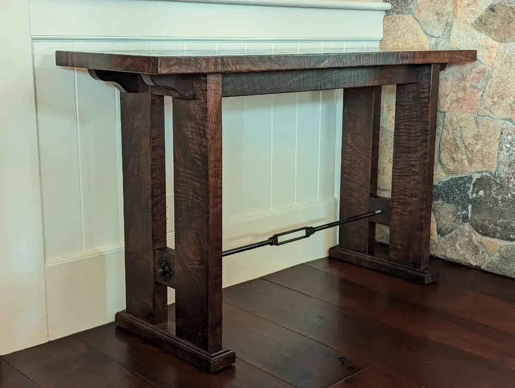 Custom table in rare highly figured California walnut. The metal trestle detail echoes architectural detailing in the room. Design in Wood